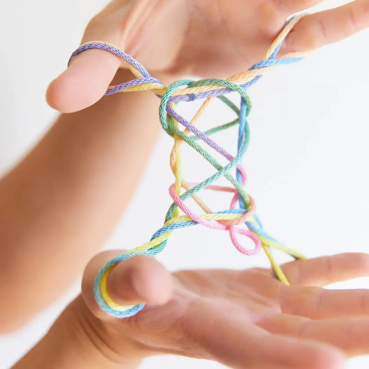 Ladder string figure close up made with rainbow string and held between two hands