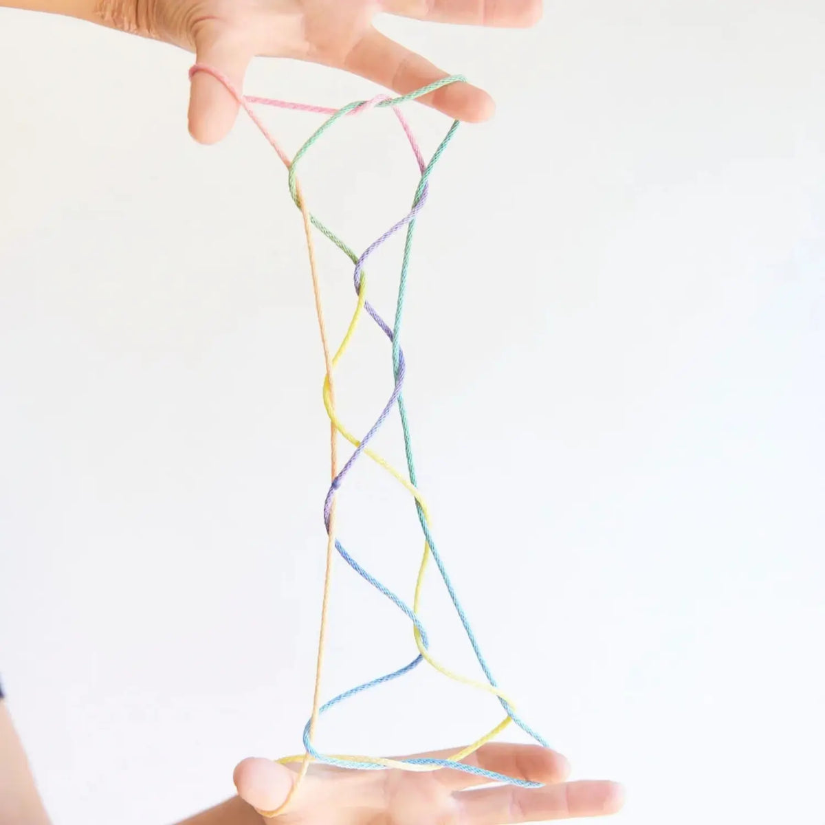 Tall string figure made with rainbow string and held between hands