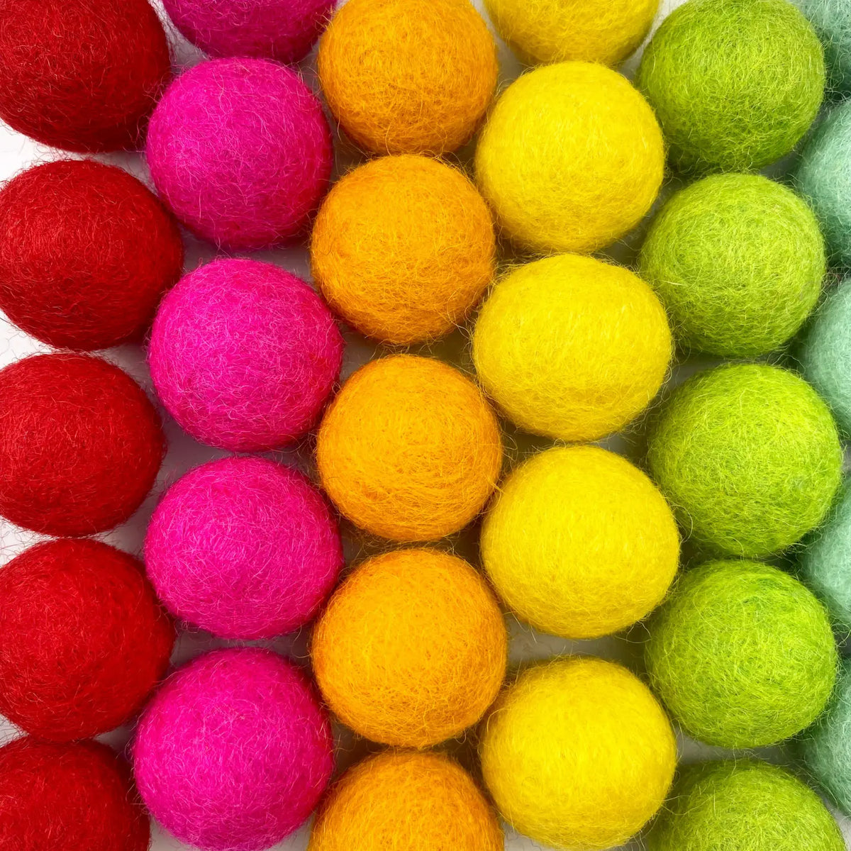 Close-up of red, pink, orange, yellow, and green wool felt balls.