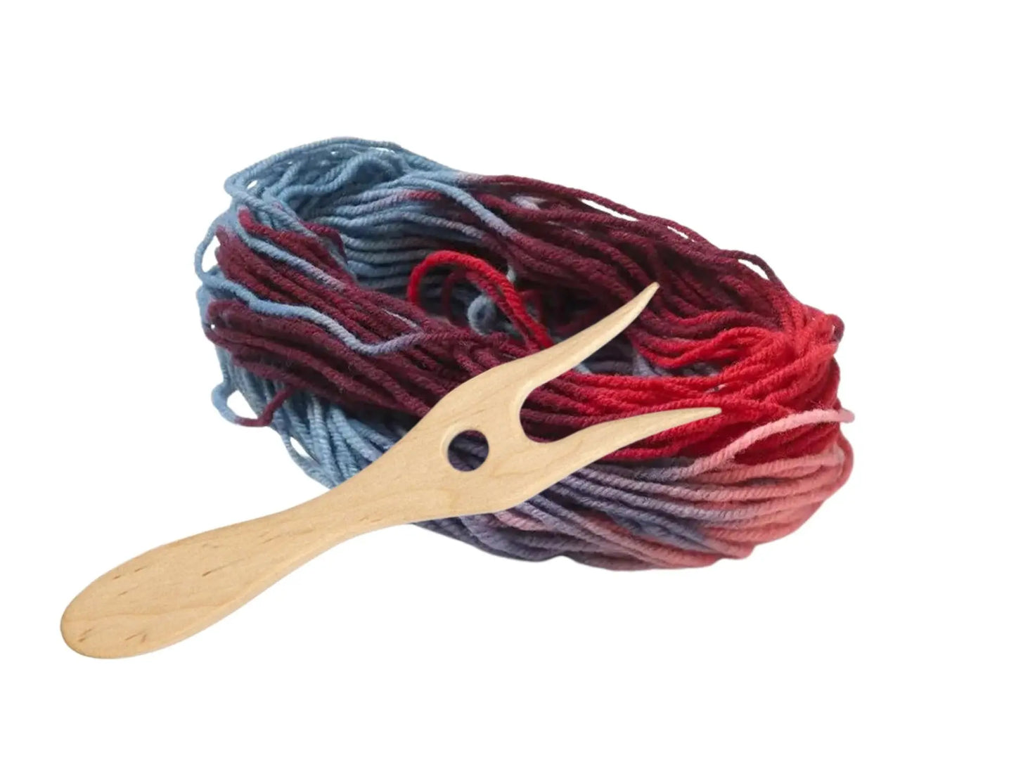 Rainbow yarn in blue, purple, red, and pink with a wooden knitting fork  in natural wood for kids