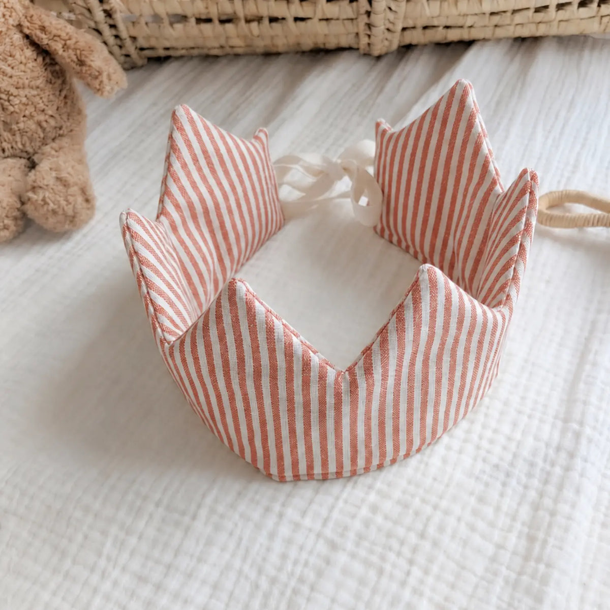 Red striped linen children's crown shown open on a soft neutral nursery background