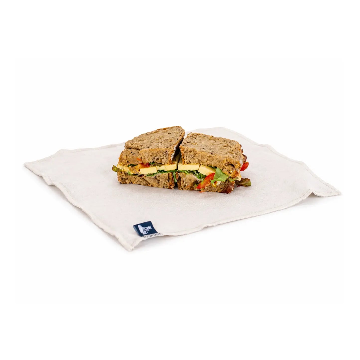 Open reusable linen sandwich wrap with food-grade lining holding a sliced sandwich on a white background.