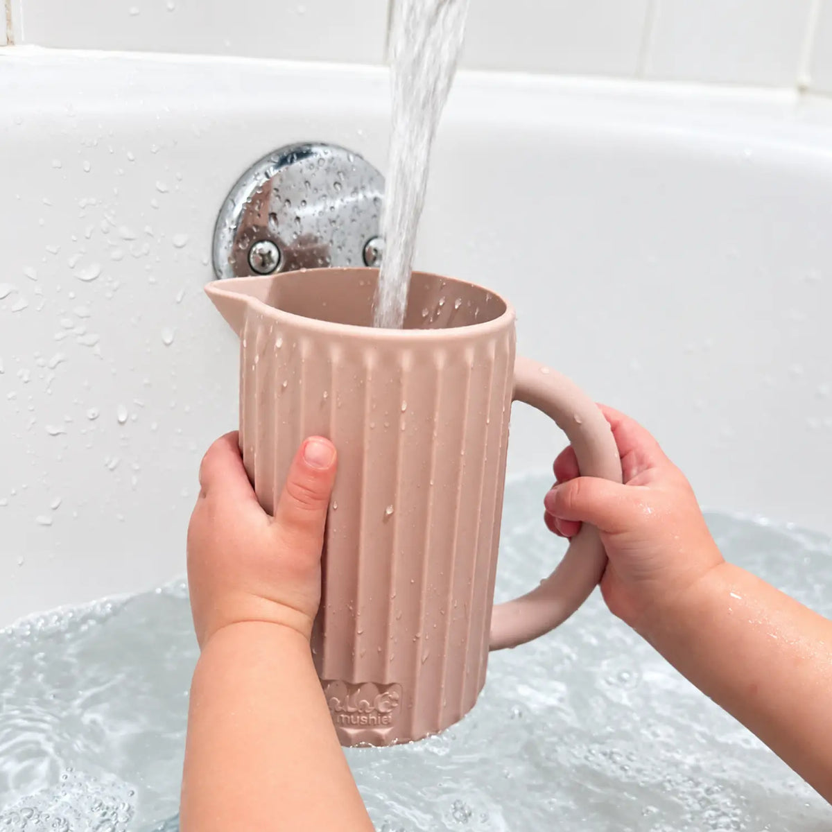 Petal pink Ripple silicone rinse cup being filled with water during bath time.