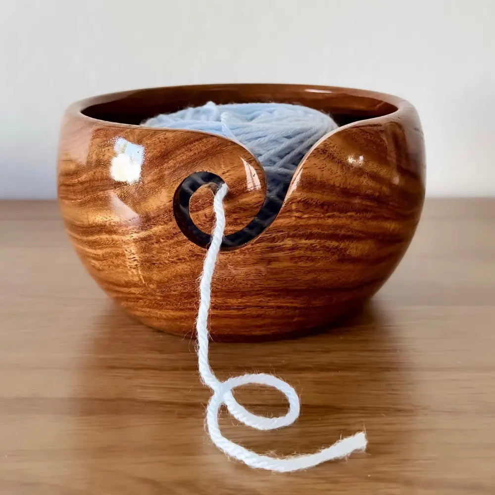Wooden yarn bowl with white yarn on a wooden surface