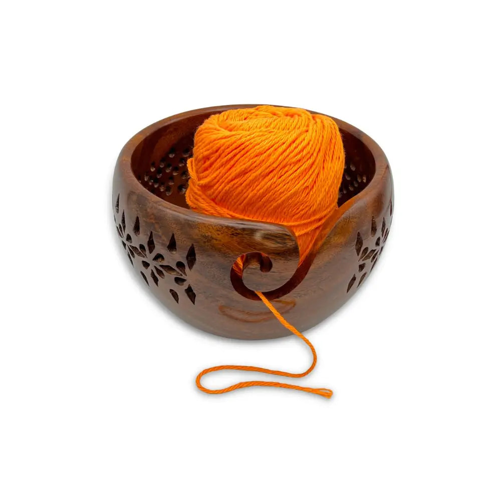 Wooden yarn bowl with an orange ball of yarn on a white background