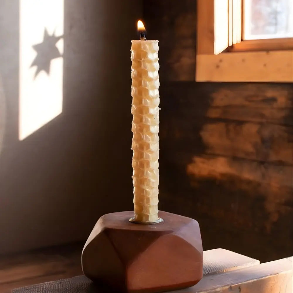 Tall textured candle in a wooden holder on a rustic background