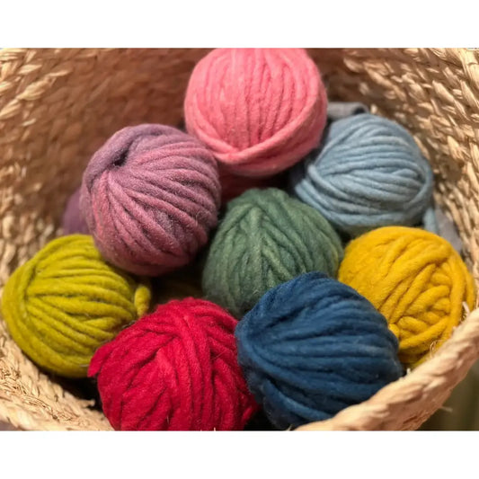Assorted colorful yarn balls in a woven basket