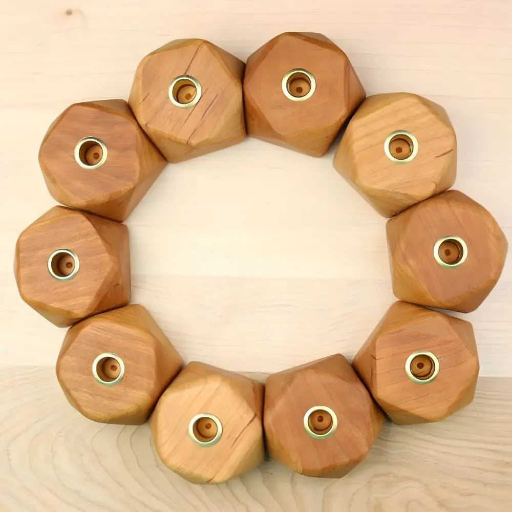 Wooden geometric candle holder with circular cutouts arranged in a circle on a wooden surface.
