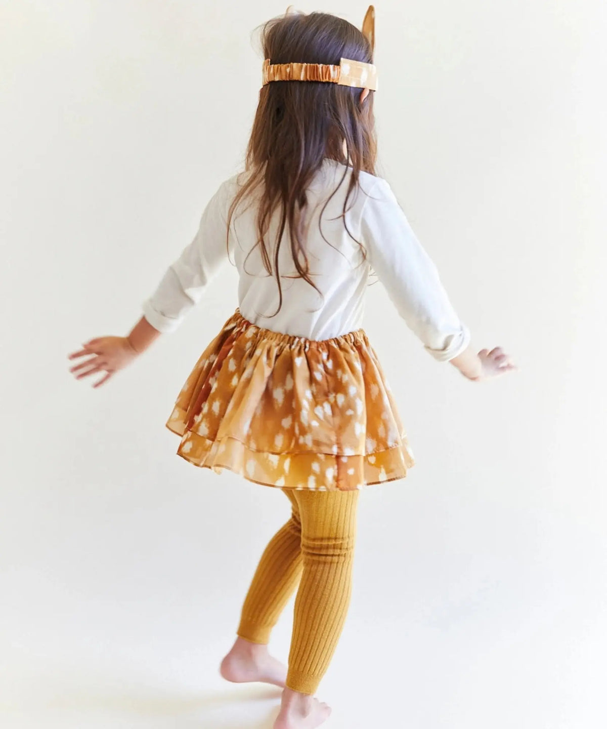 Back view of a child wearing Sarah’s Silks fawn ears with a matching Playsilk skirt