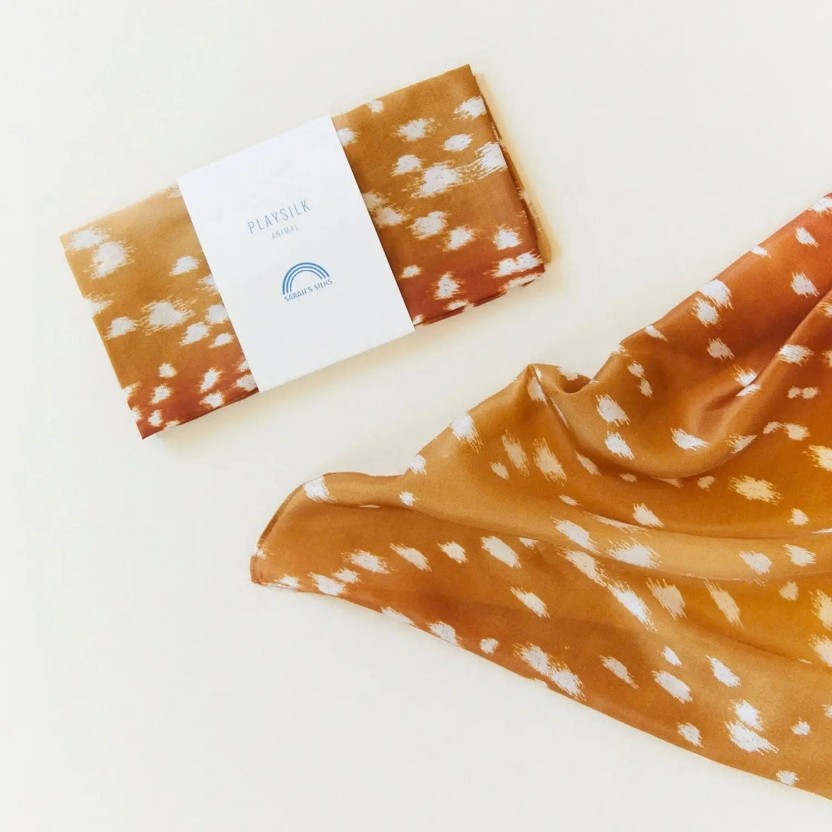 Folded Sarah’s Silks fawn-print Playsilk with the fabric draped beside it