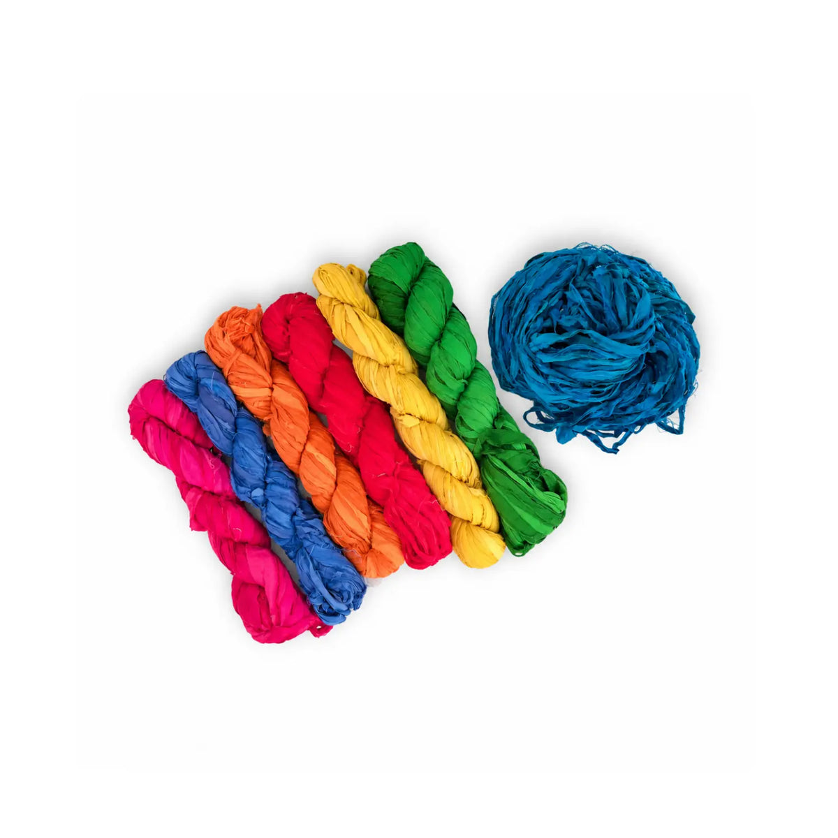 Twisted skeins of recycled sari silk chiffon ribbon in pink, blue, orange, red, and yellow beside a loose teal bundle