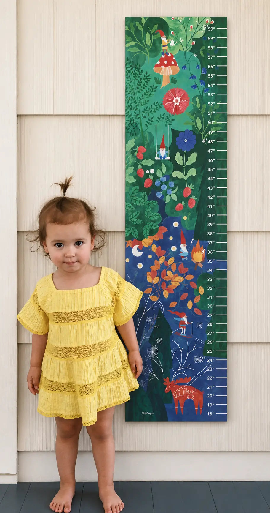 Young child standing beside a Scandinavian-style gnome growth chart with colorful seasonal woodland scene
