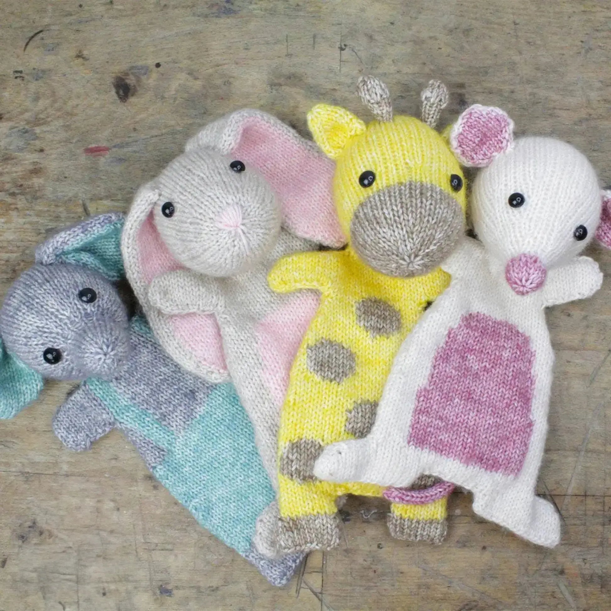Finished knitted animals from Scheepjes yarn kits including bunny, lamb, and giraffe