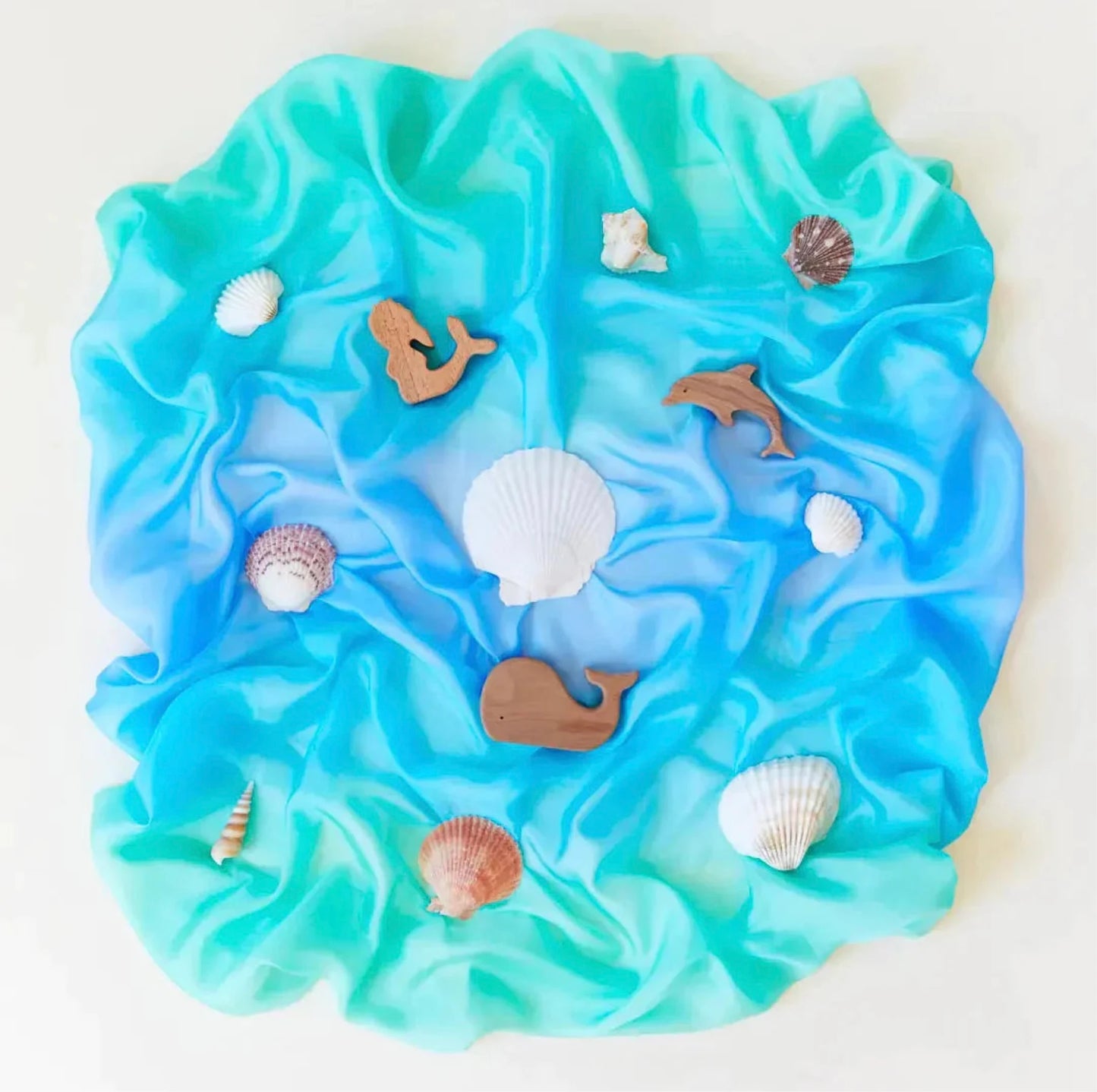 Enchanted playsilk in Sea Colorway with seashells and wooden toys on top