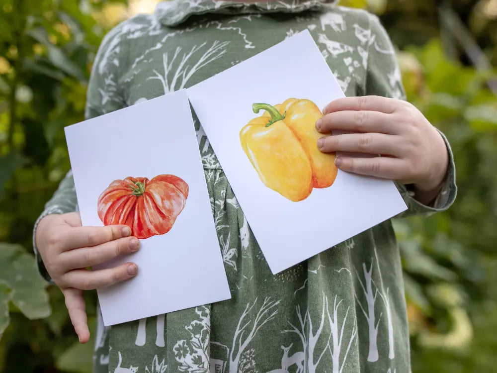 Child holding tomato produce learning card outdoors