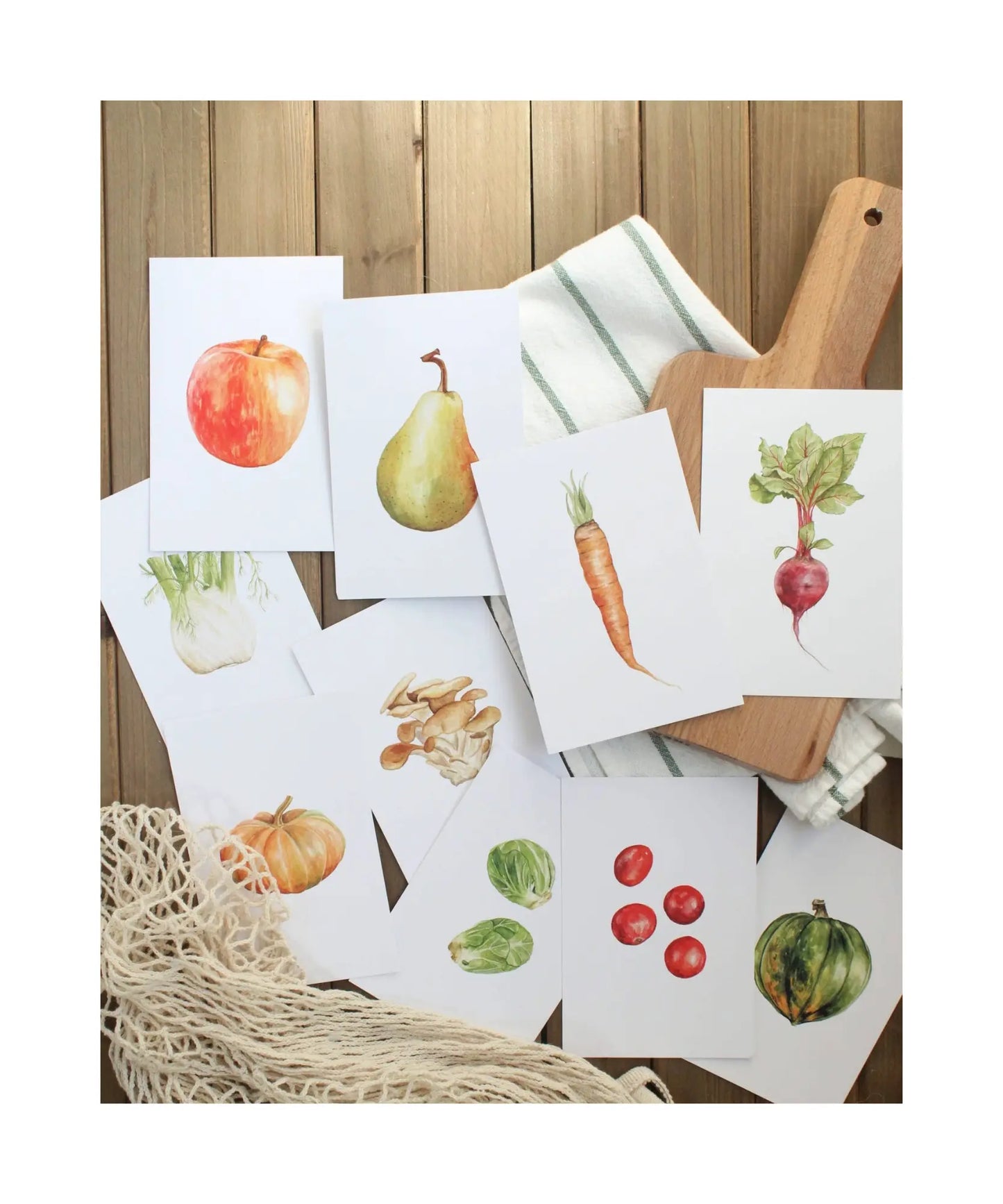Seasonal produce learning cards with watercolor fruits and vegetables laid out on table