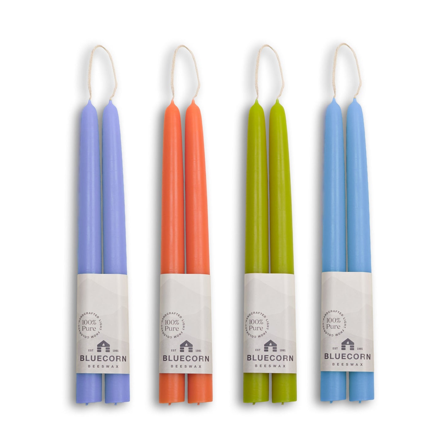 Set of four colorful candles with white wicks on a white background, branded 'Bluecorn'.