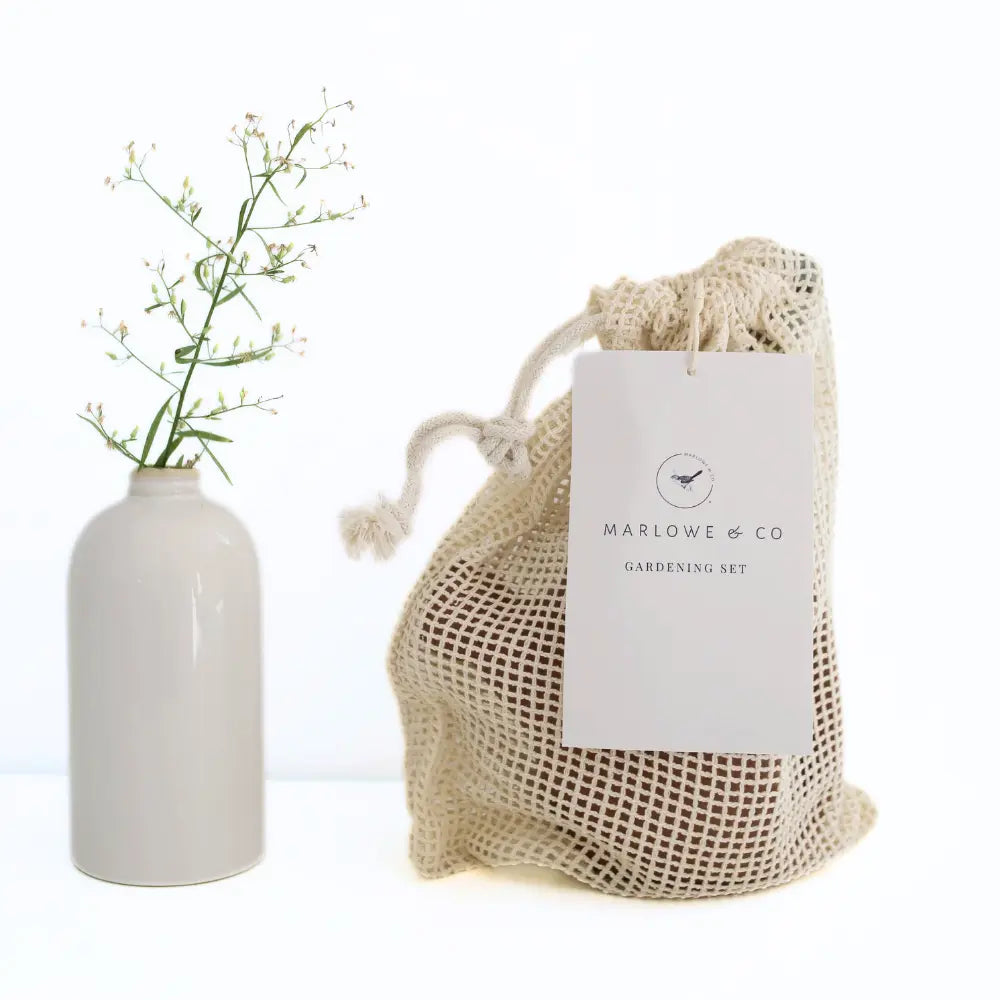 White vase with greenery next to a mesh storage bag labeled 'Marlowe & Co' on a white background