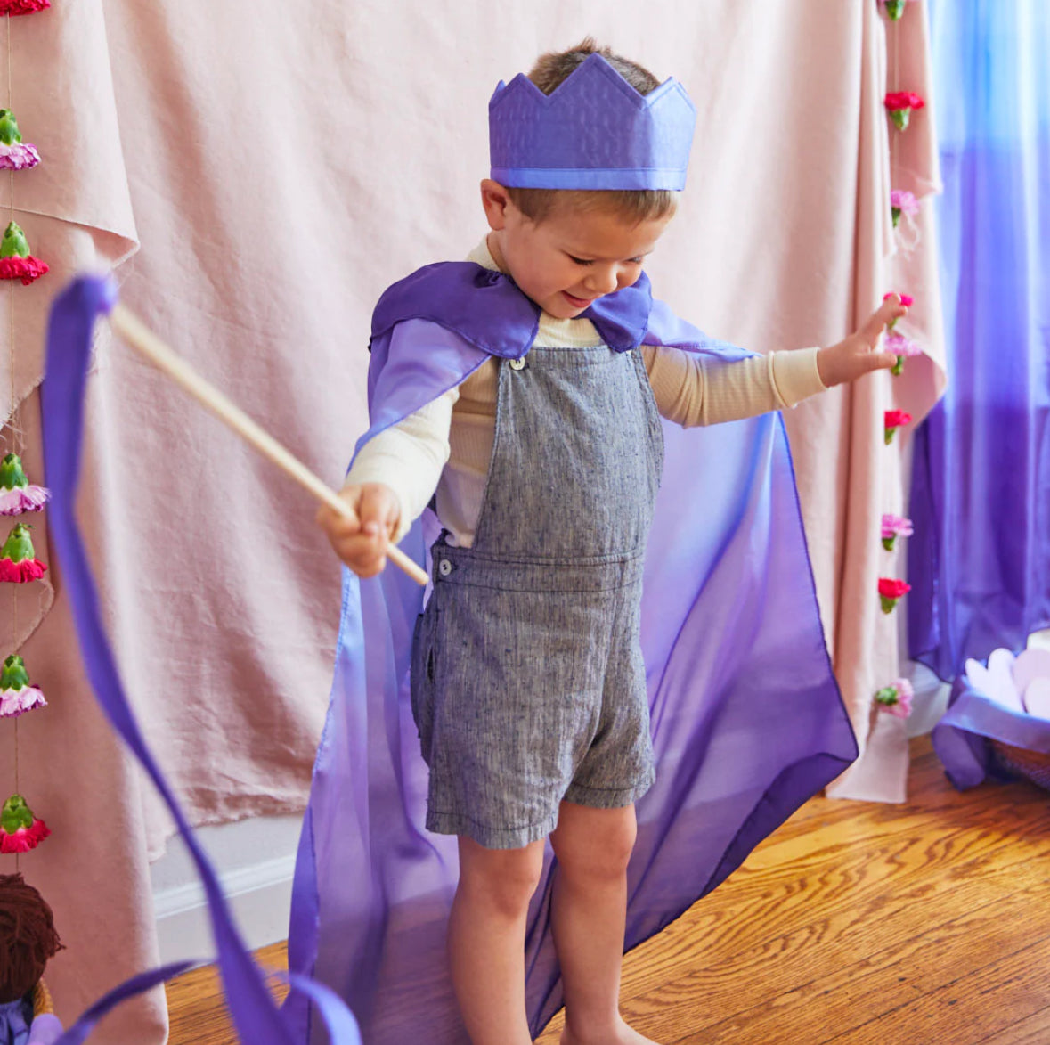 Child wearing cape, crown and holding a streamer in the Butterfly colorway