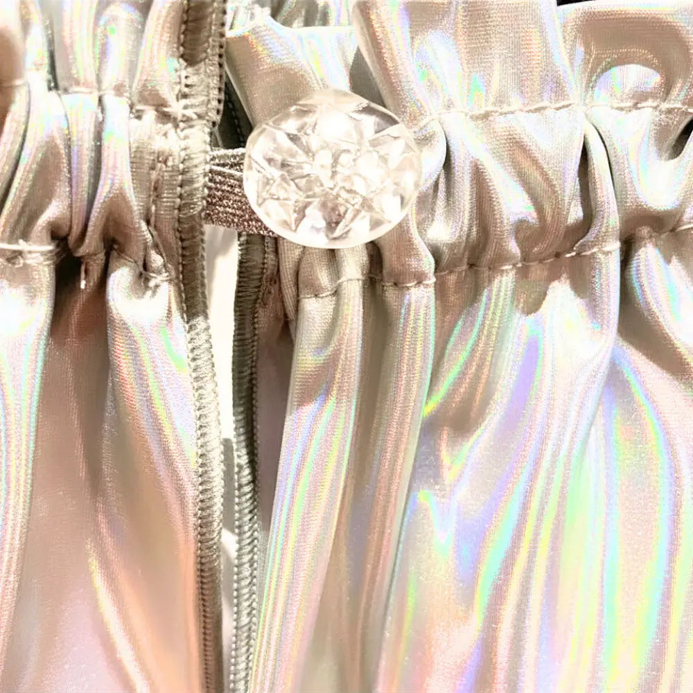 Close-up of a shiny, iridescent fabric with a zipper and decorative button.