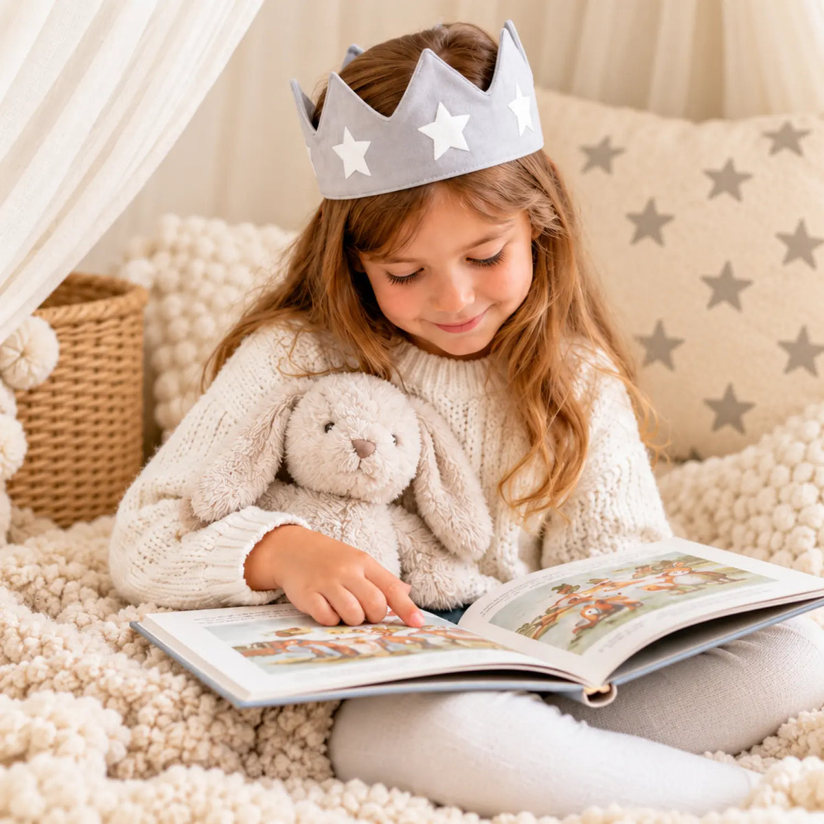 Child wearing a silver star cotton canvas crown while reading with a stuffed bunny