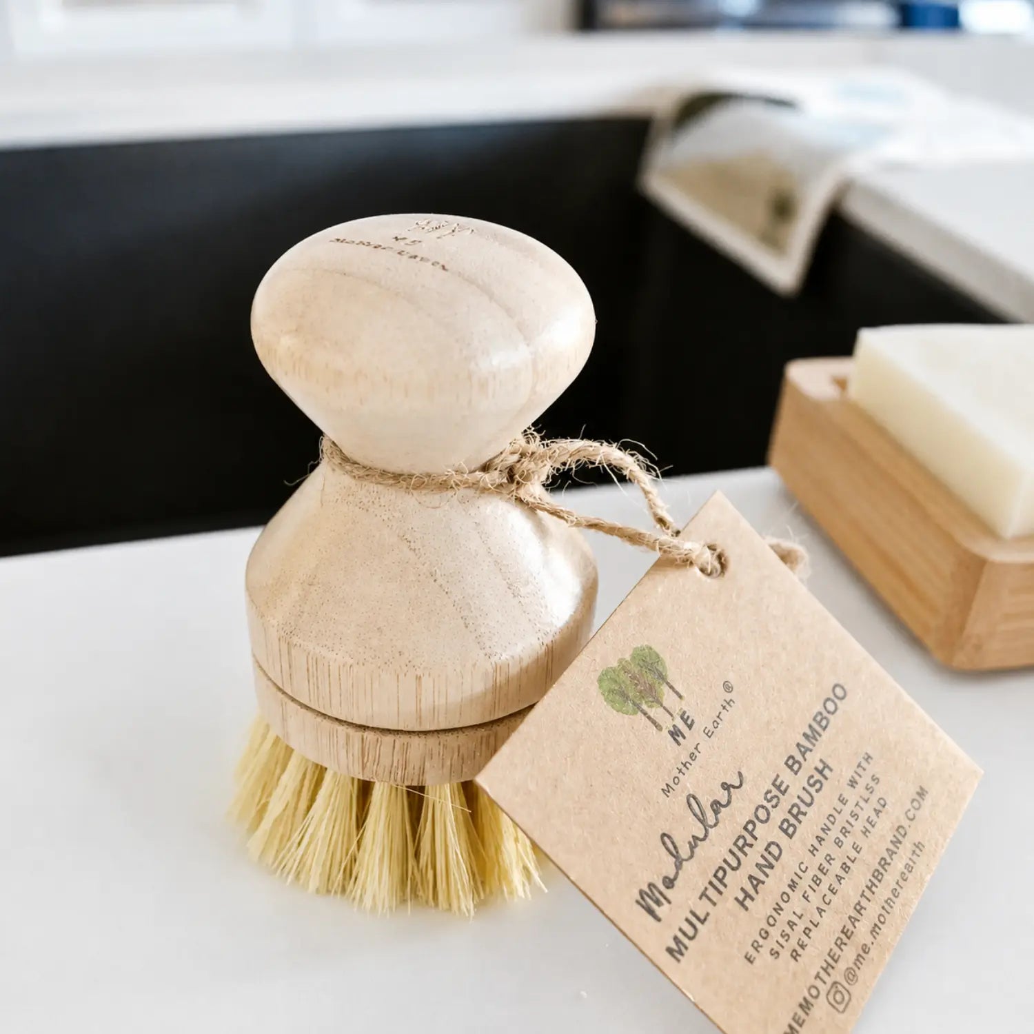 Sisal bamboo dish brush with replaceable head and kraft product tag on a kitchen counter.