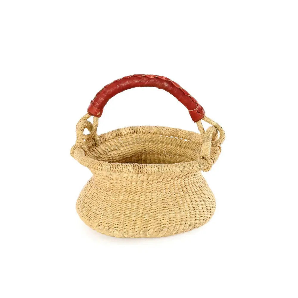 Small handwoven grass basket with swing handle raised, showing woven texture and basket shape