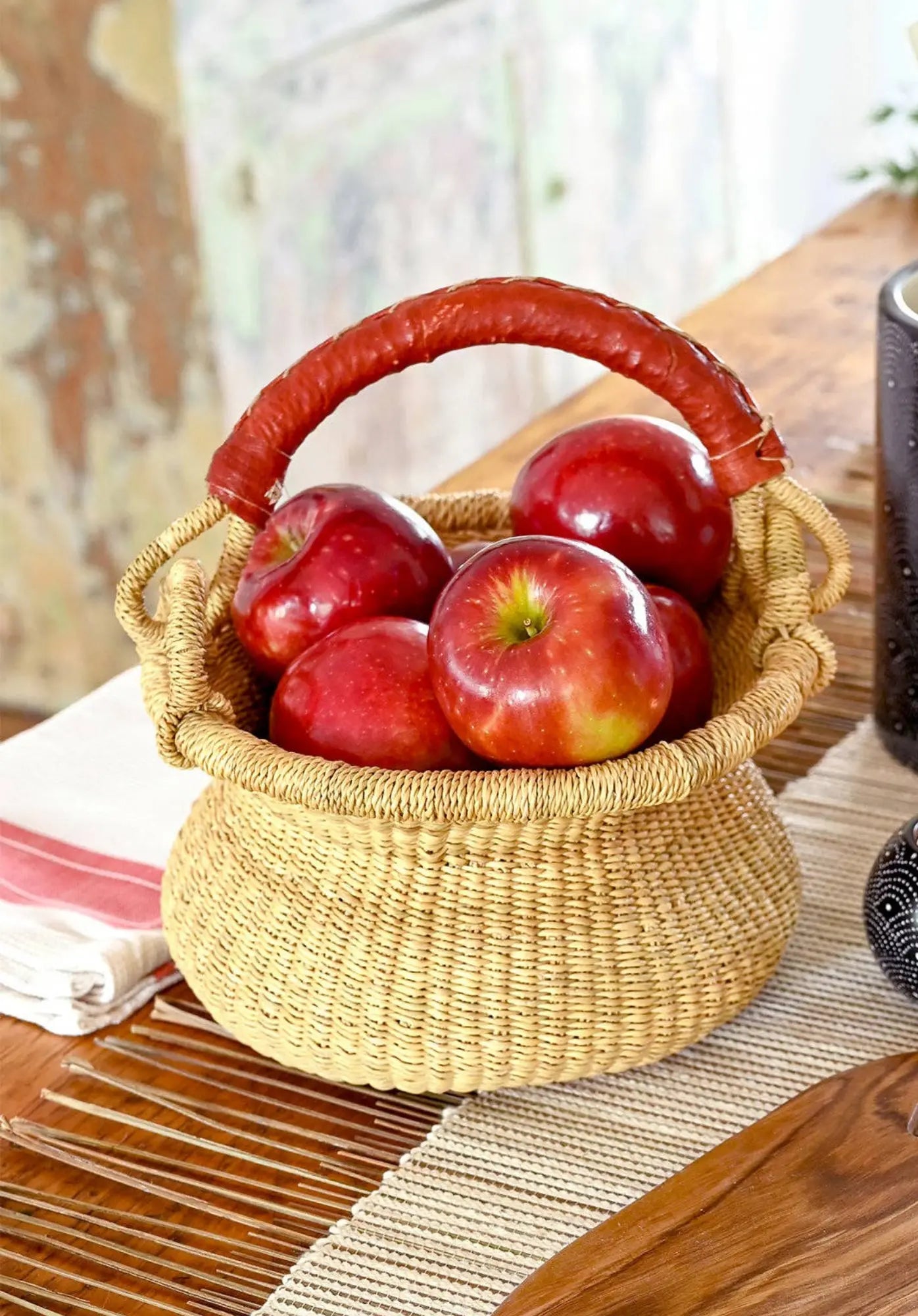 Woven gathering basket with red apples on a wooden table