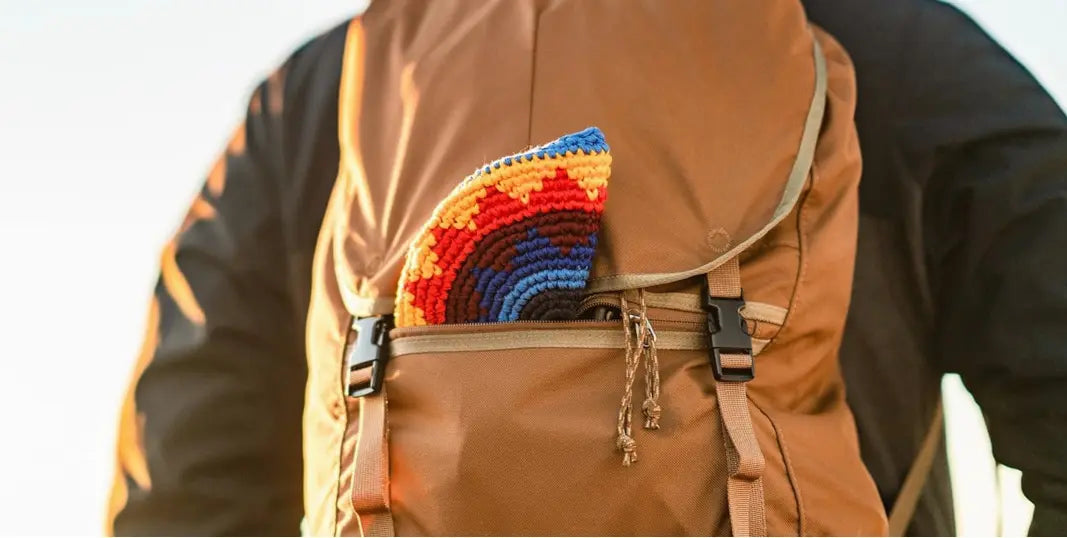 Person wearing a brown jacket with a colorful knitted soft flying disc in the front pocket against a blurred background