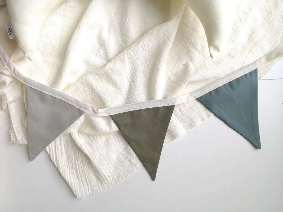Close-up of the linen pennant garland showing muted gray, olive and blue flags.