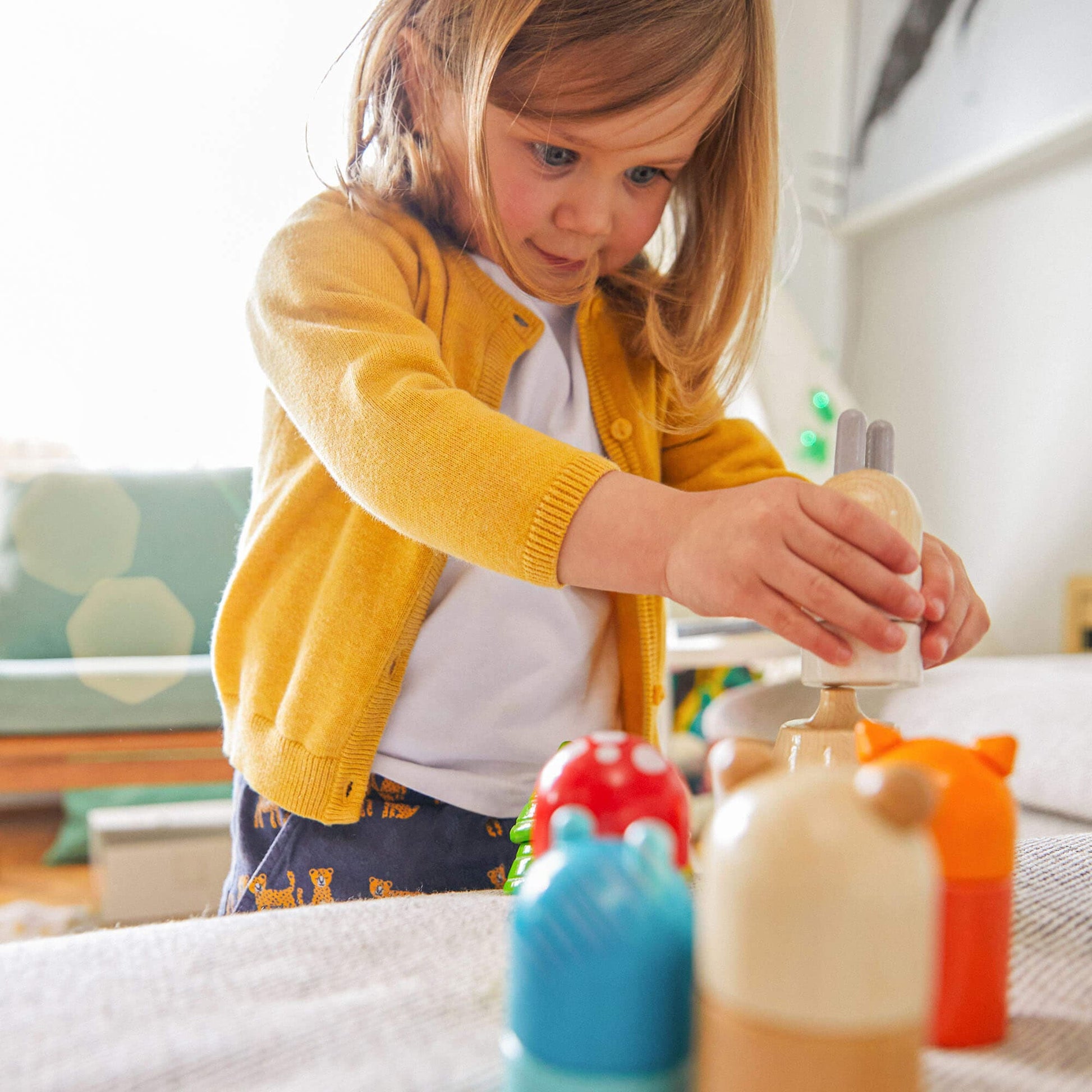 Child playing with colorful wooden toys on a bed