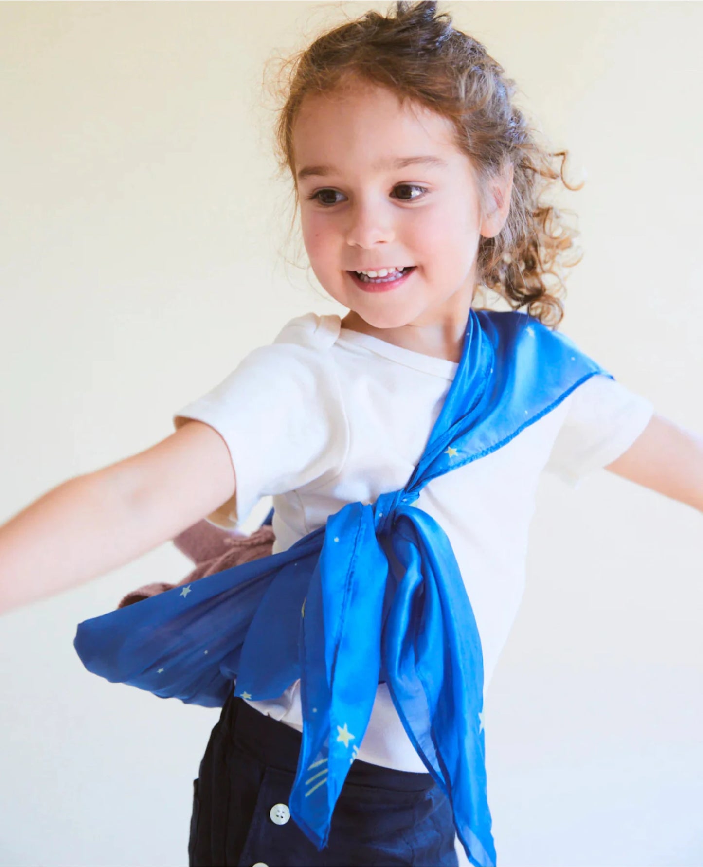 A girl wearing a starry night enchanted playsilk as a baby doll carrier