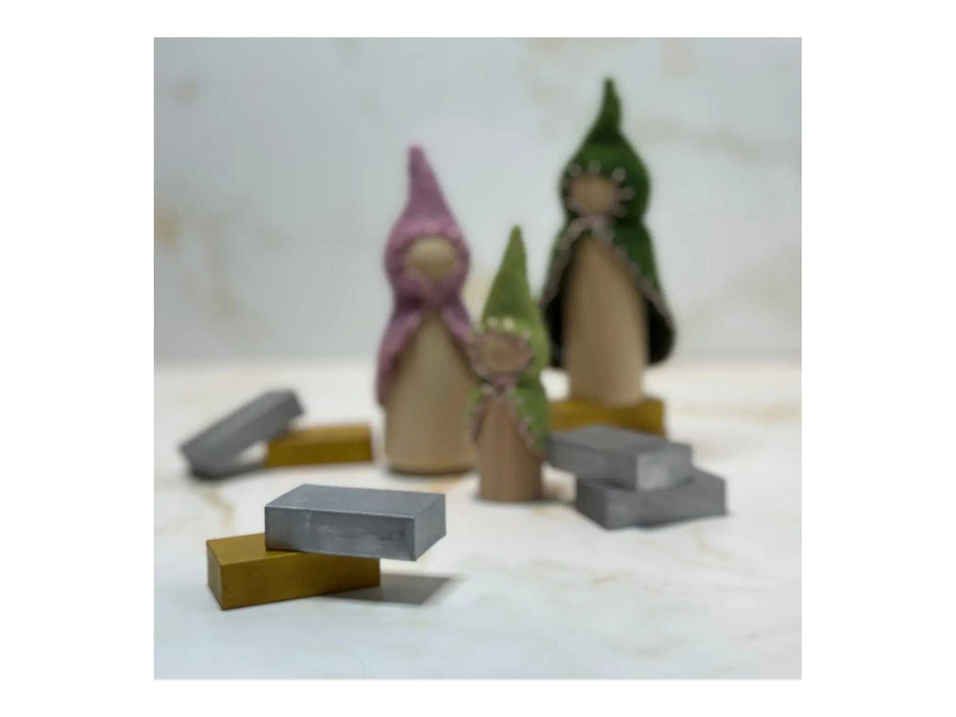 Wooden figures with hats and Stockmar silver and gold block crayons on a light background