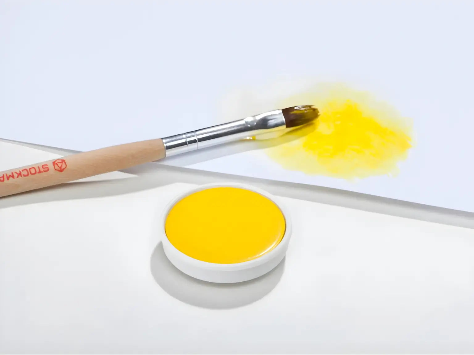 Lemon Yellow Stockmar opaque paint with a brush on a white background