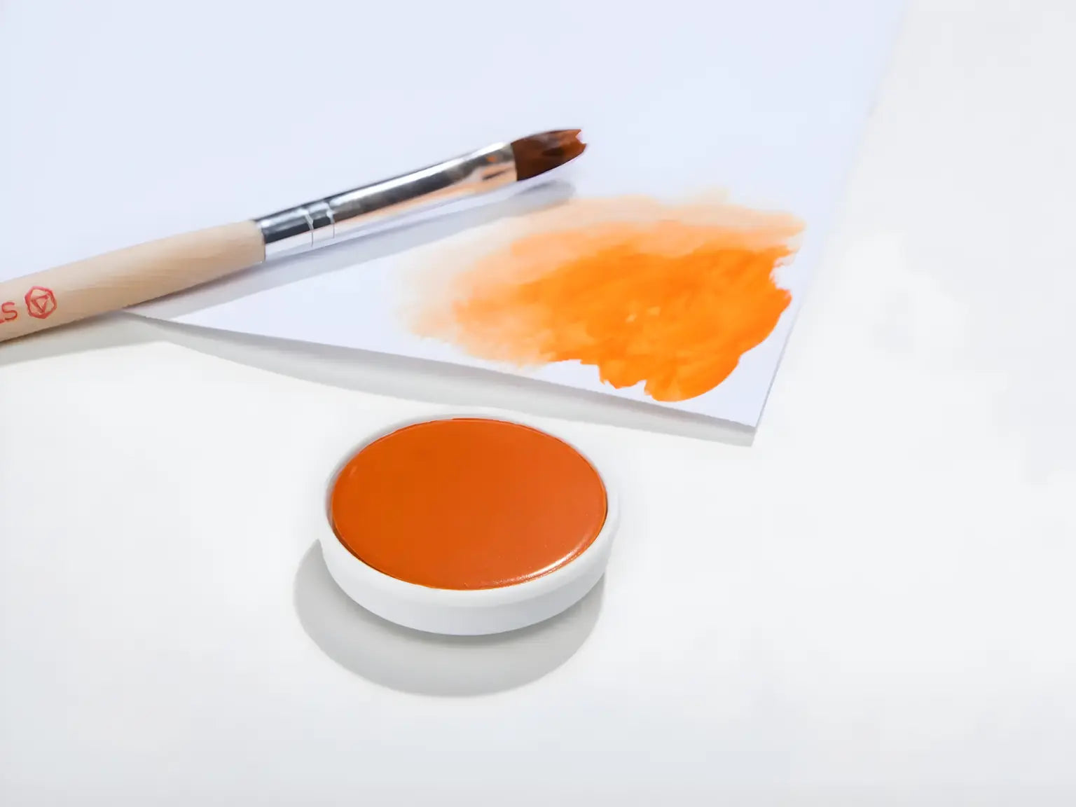 Orange Stockmar opaque paint with a brush on a white background