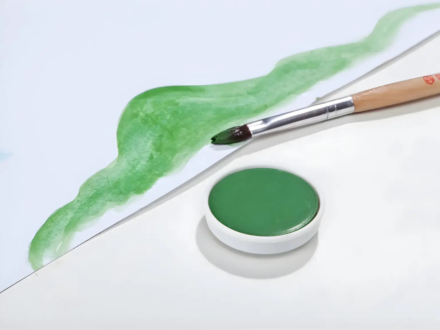 Sap Green Stockmar opaque paint with a brush on a white background