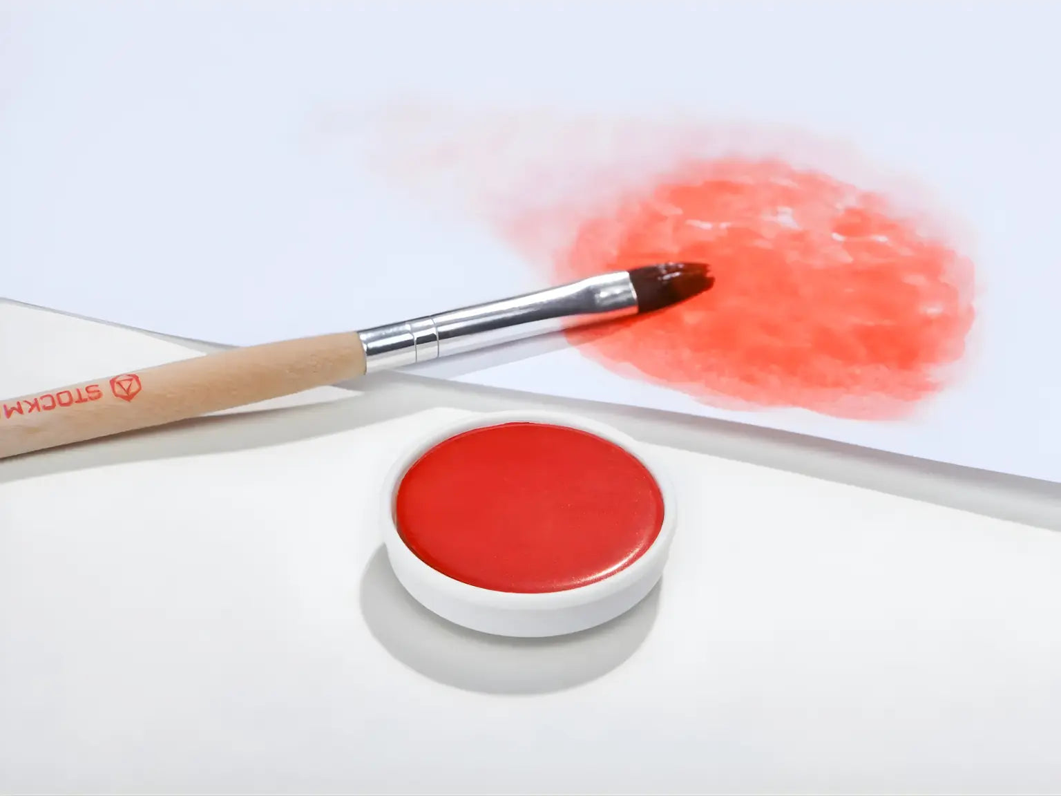 Vermilion Stockmar opaque paint with a brush on a white background