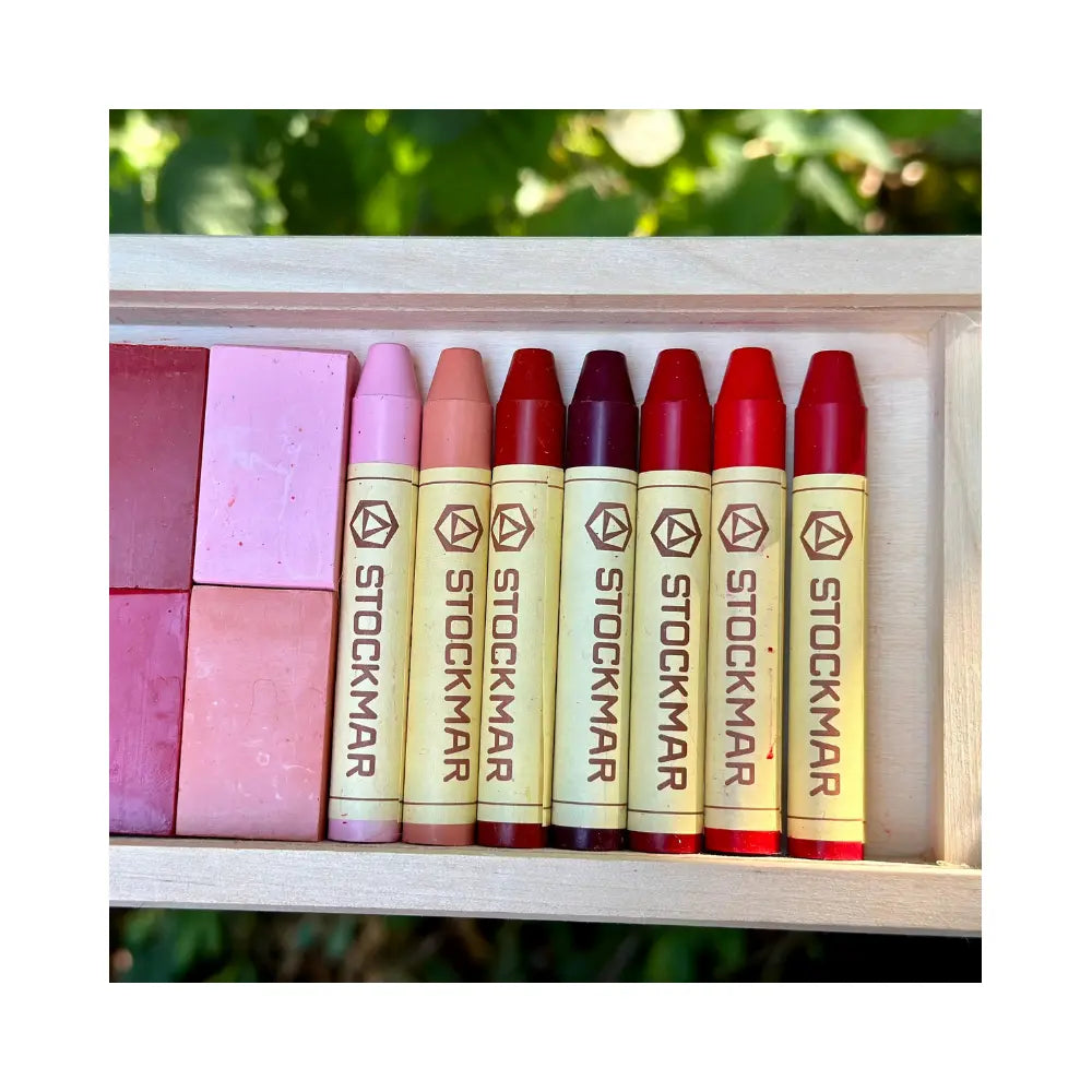 Set of Stockmar stick crayons in various colors displayed in a wooden box with a natural background.