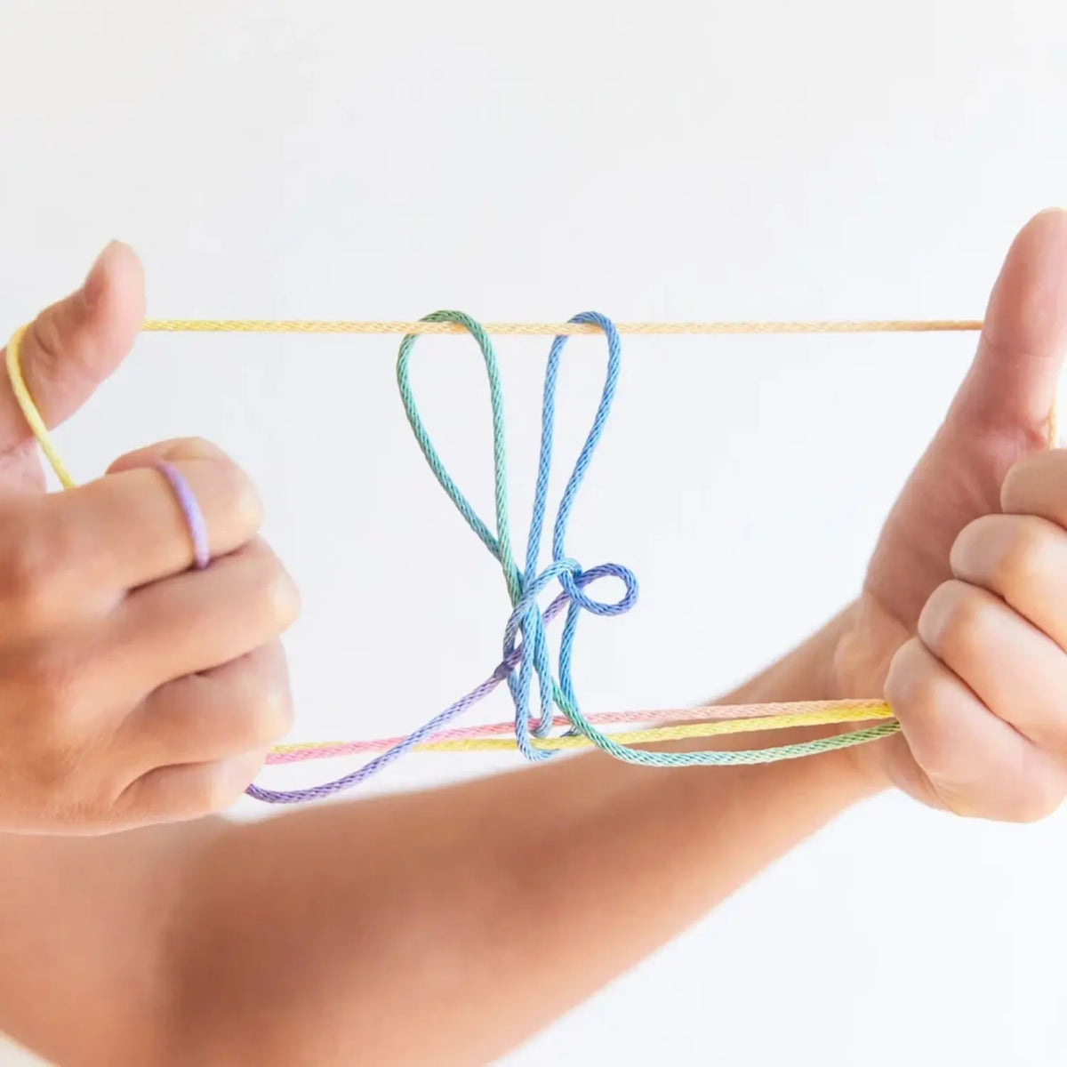 Loop string figure made with rainbow string and held between two hands