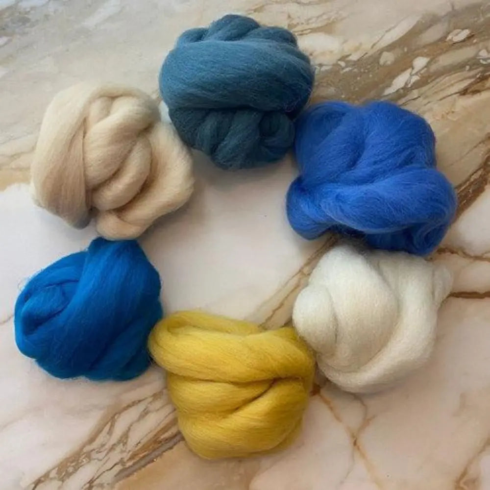 Six skeins of wool top spinning wool in blues, greens, golden yellow, white, and tan