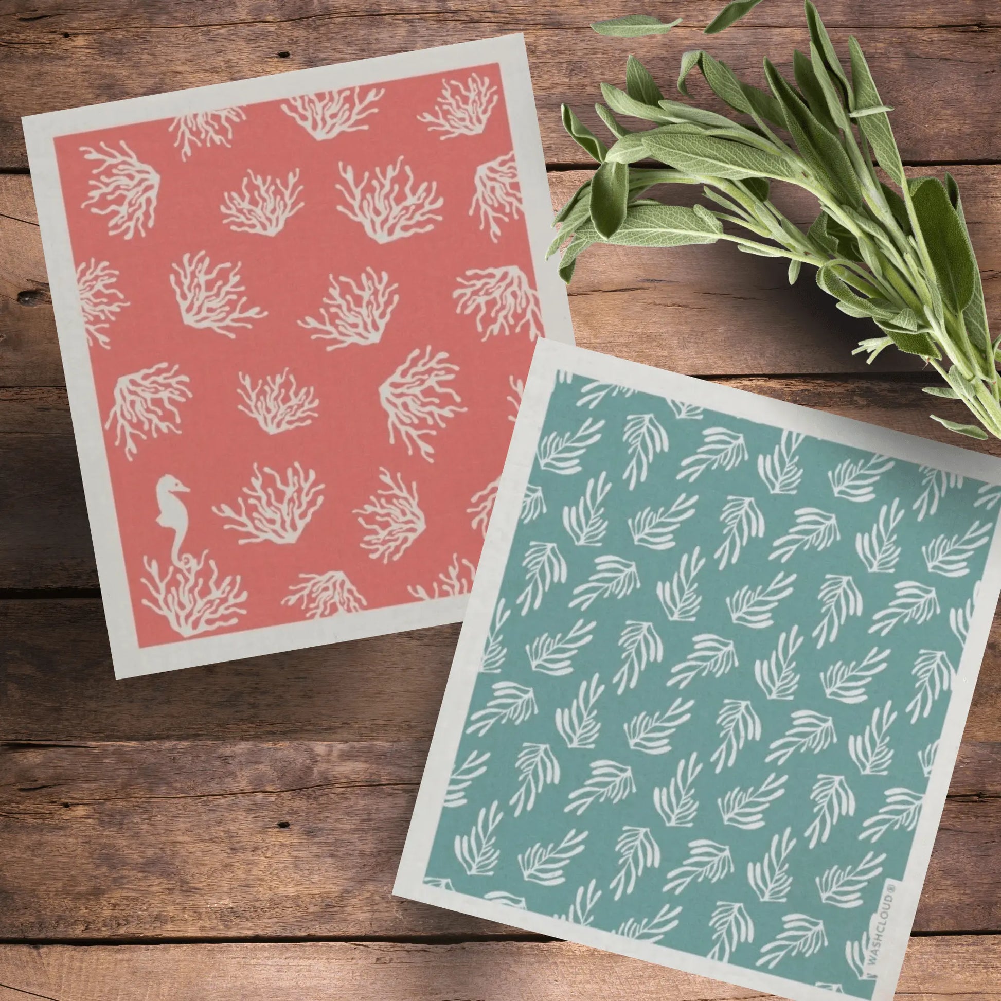Swedish Dishcloth Pair with Coral and Kelp - Sea Theme - on a wooden table with spring of herbs