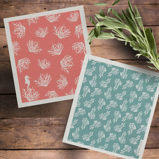 Swedish Dishcloth Pair with Coral and Kelp - Sea Theme - on a wooden table with spring of herbs