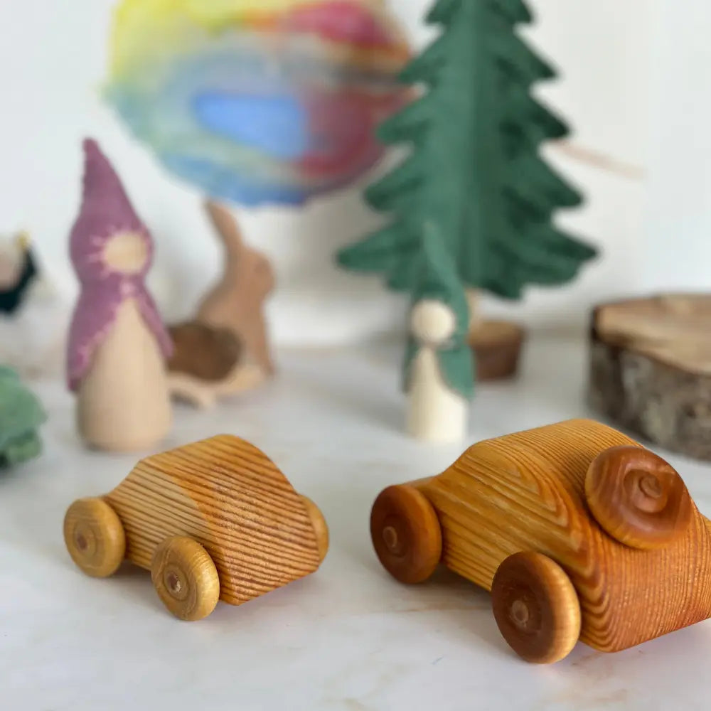 Two wooden toy cars on a surface with decorative items in the background.