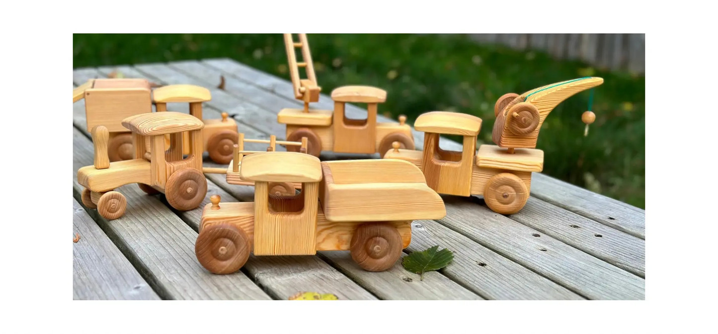 Set of wooden toy trucks on a wooden surface with a blurred natural background