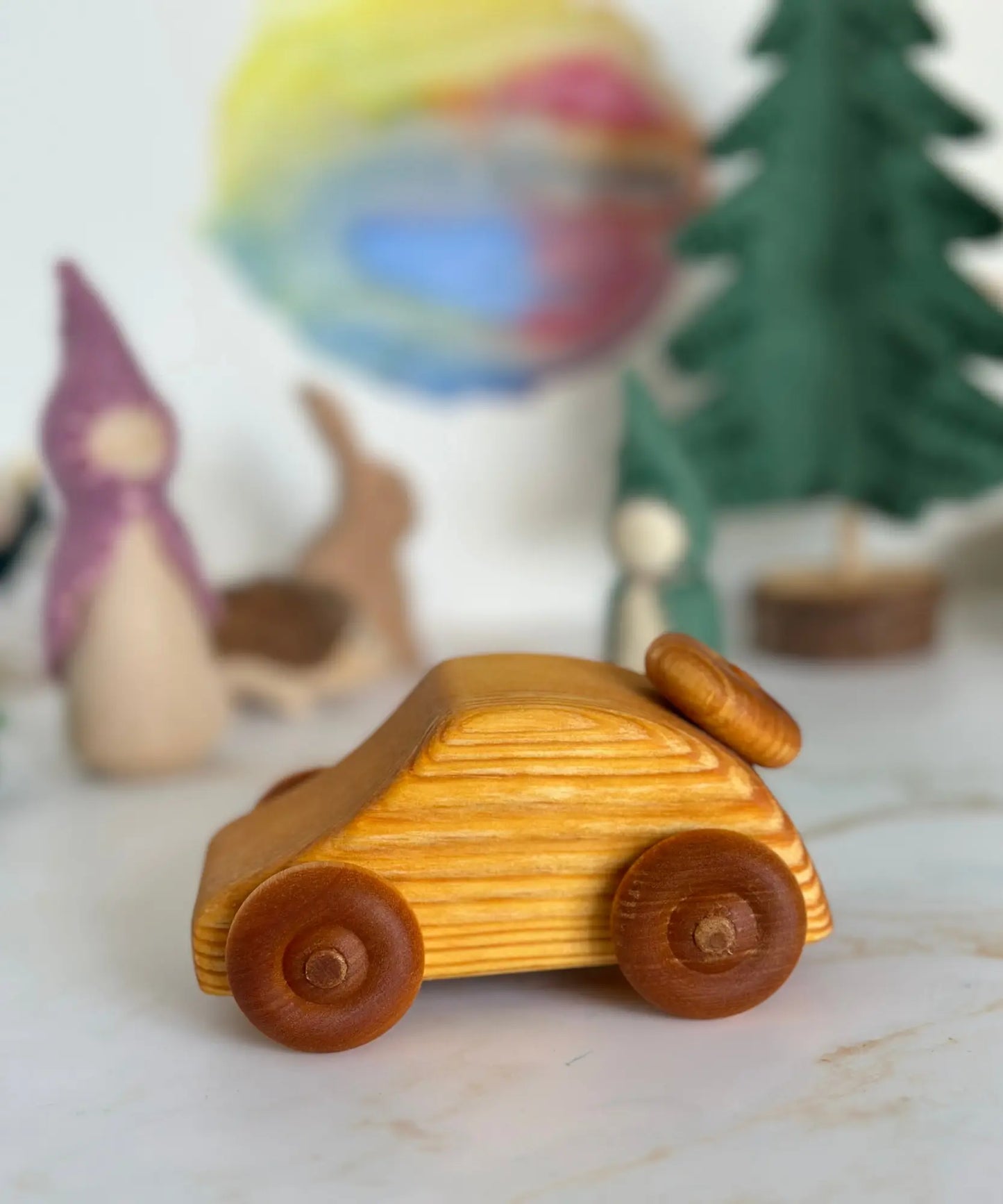 Wooden toy car on a light surface with decorative items in the background