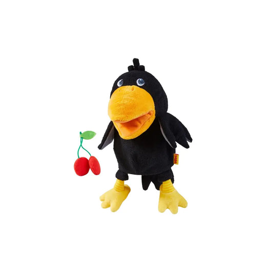 Child laughing while playing with Theo the Raven glove puppet by HABA