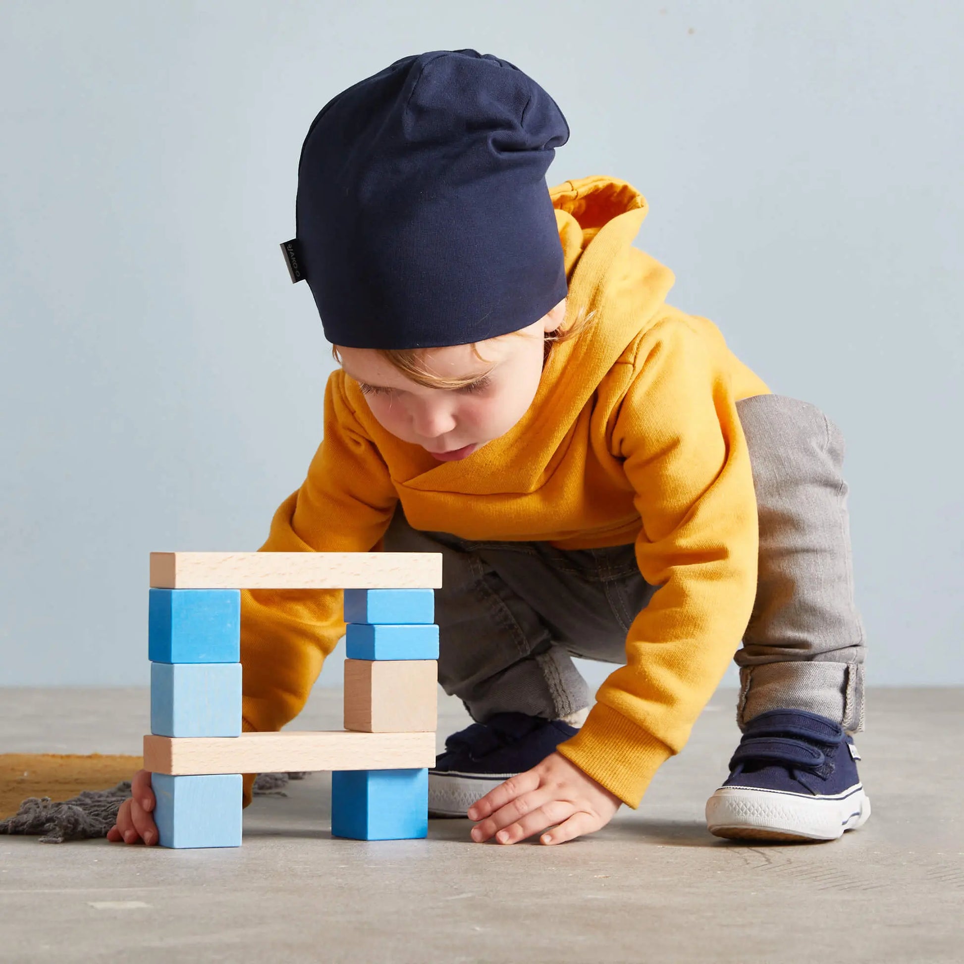 Child playing with colorful building blocks on a wooden floor.
