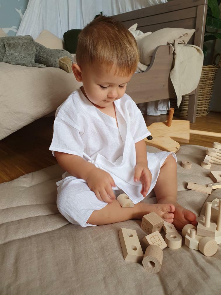 Toddler playing with natural wooden train and stacking blocks