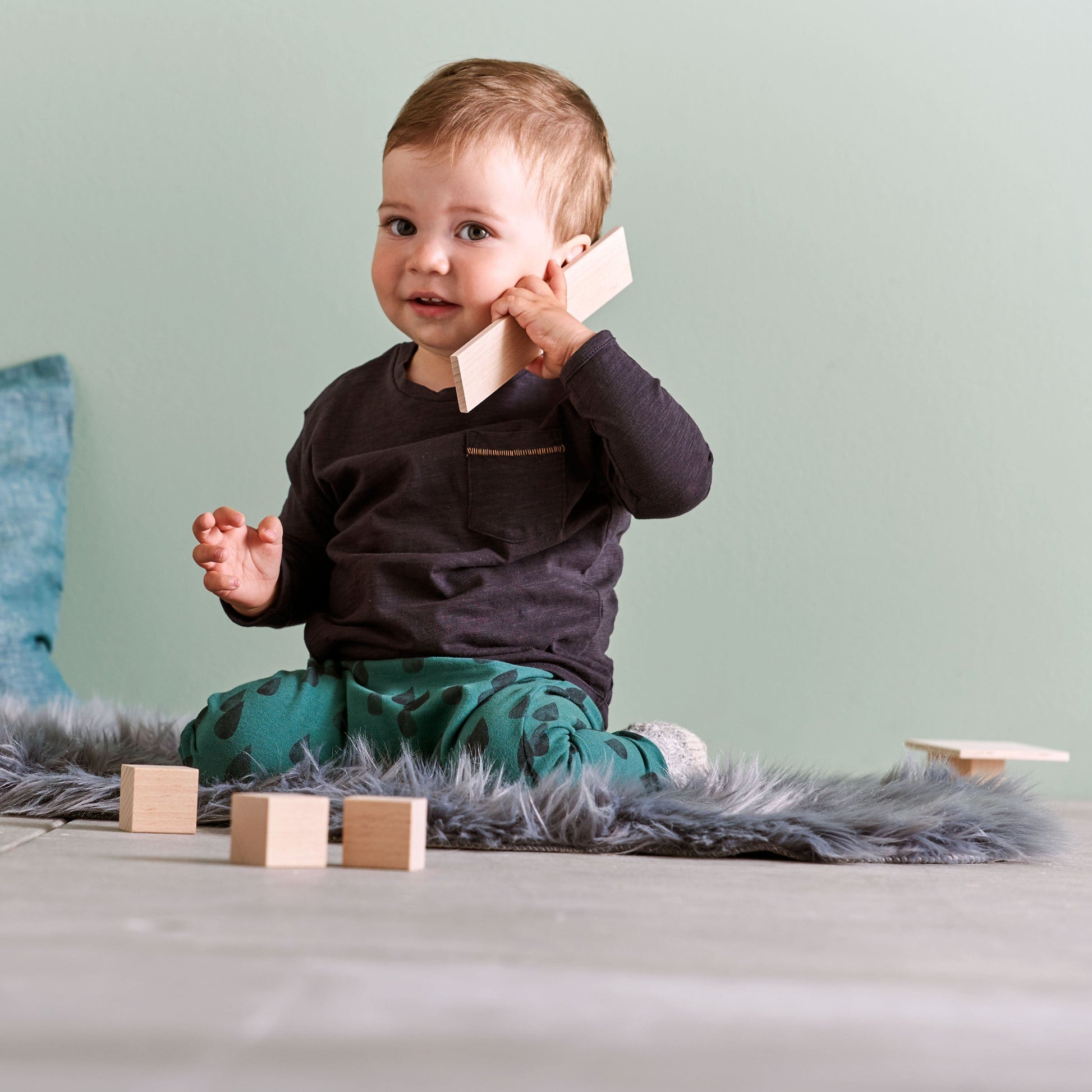 Young child sitting and playing with wooden building blocks on floor