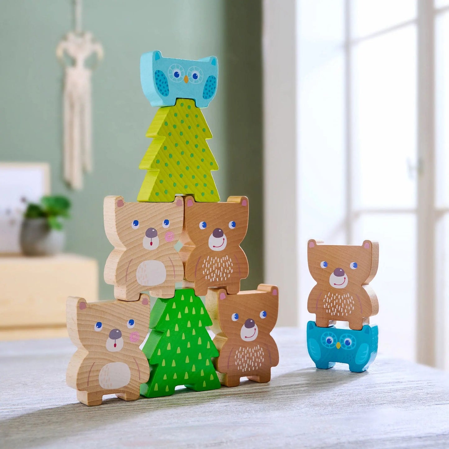 Set of wooden animal figurines with trees on a light surface